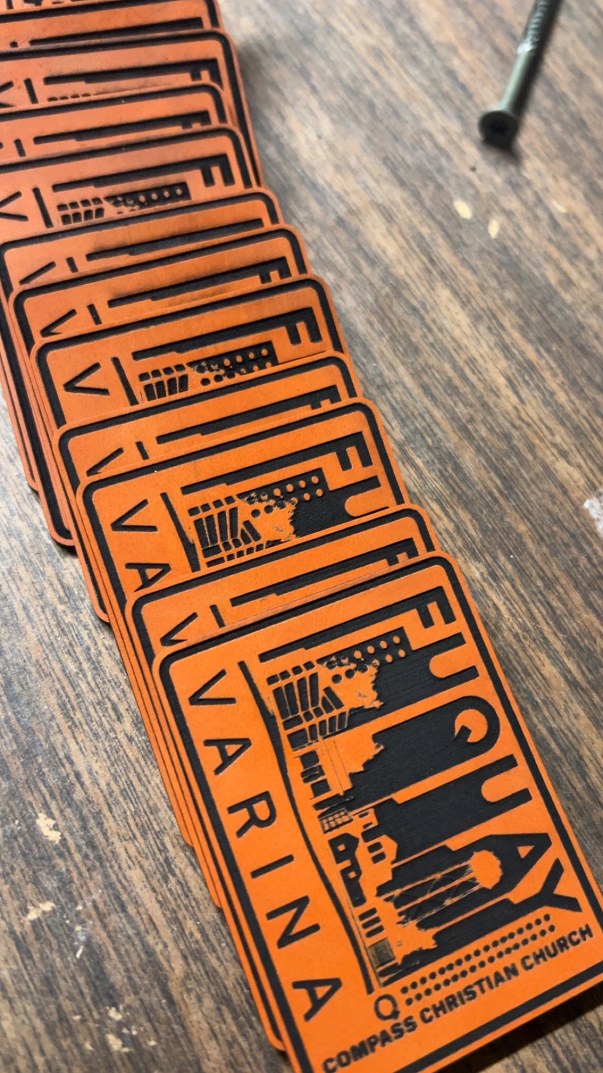 A fan of orange and black rectangular cards or stickers printed with the word 'VARINA' and church-themed graphics, arranged on a wooden tabletop.