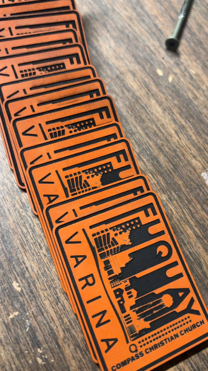 A fan of orange and black rectangular cards or stickers printed with the word 'VARINA' and church-themed graphics, arranged on a wooden tabletop.